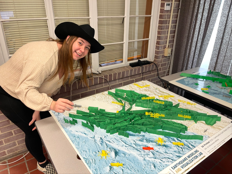 Person leaning over a 3D printed model of California faults on a map of California.